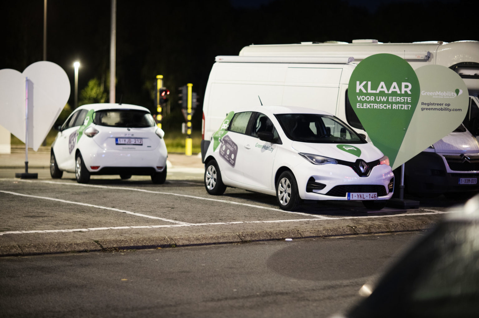 Two GreenMobility cars at night with big green hearts
