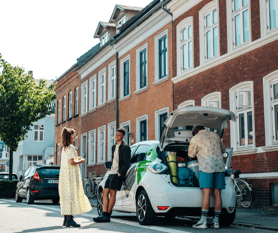 3 friends prepare the car for a trip and fill the trunk with camping stuff.