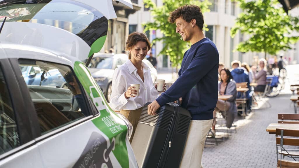 Mand og kvinde pakker kuffert i GreenMobility-bilen efter et besøg på loppemarked