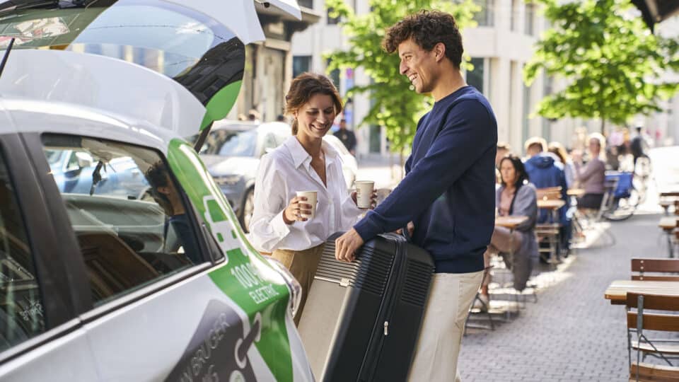 Mand og kvinde pakker kuffert i GreenMobility-bilen efter et besøg på loppemarked